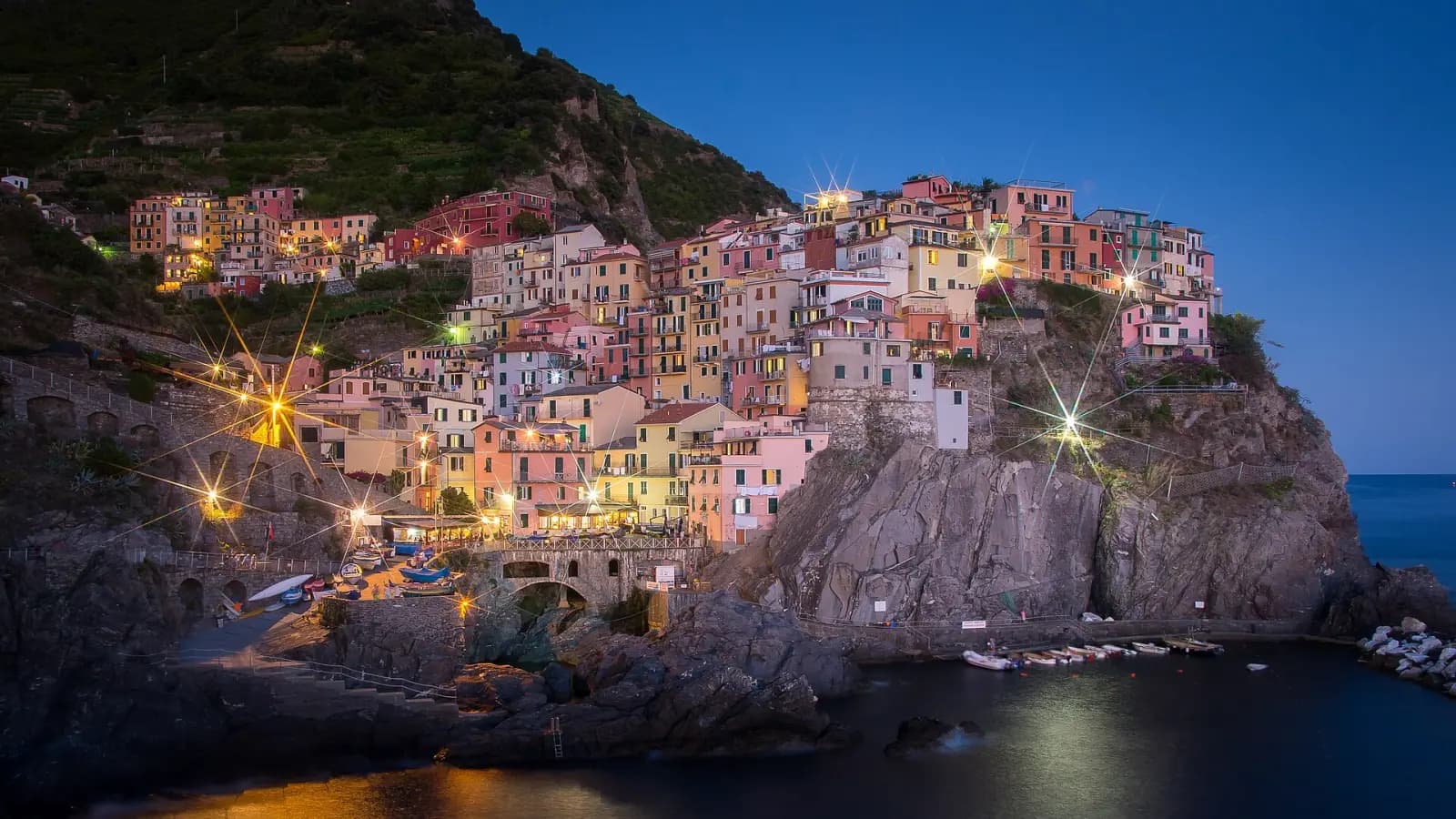 Das beleuchtete Manarola bei Einbruch der Dunkelheit, vom Küstenweg aus gesehen