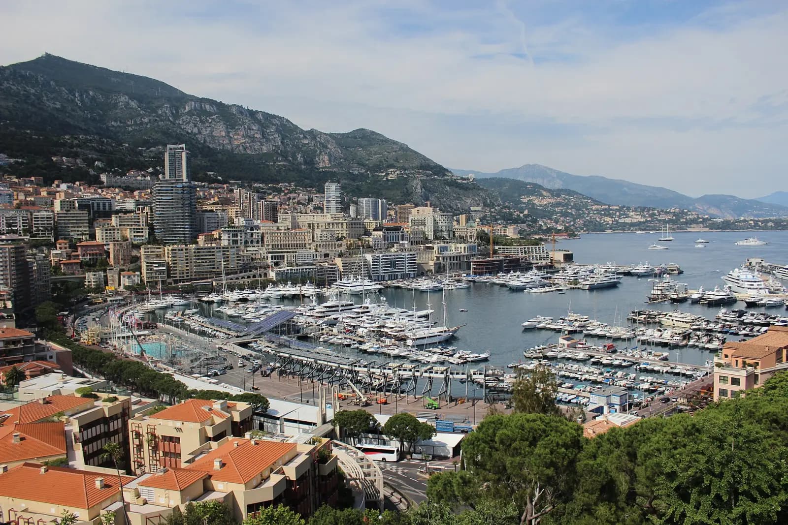 Le Port Hercule et ses yachts vus des hauteurs, avec Monte-Carlo et la montagne en arrière-plan