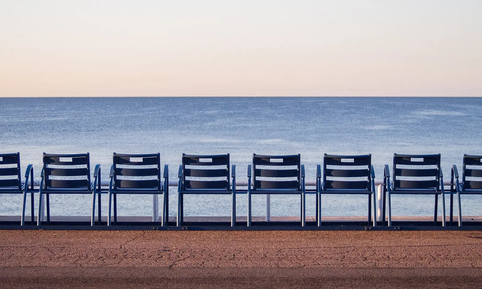 A row of blue chairs facing the sea on the Promenade des Anglais