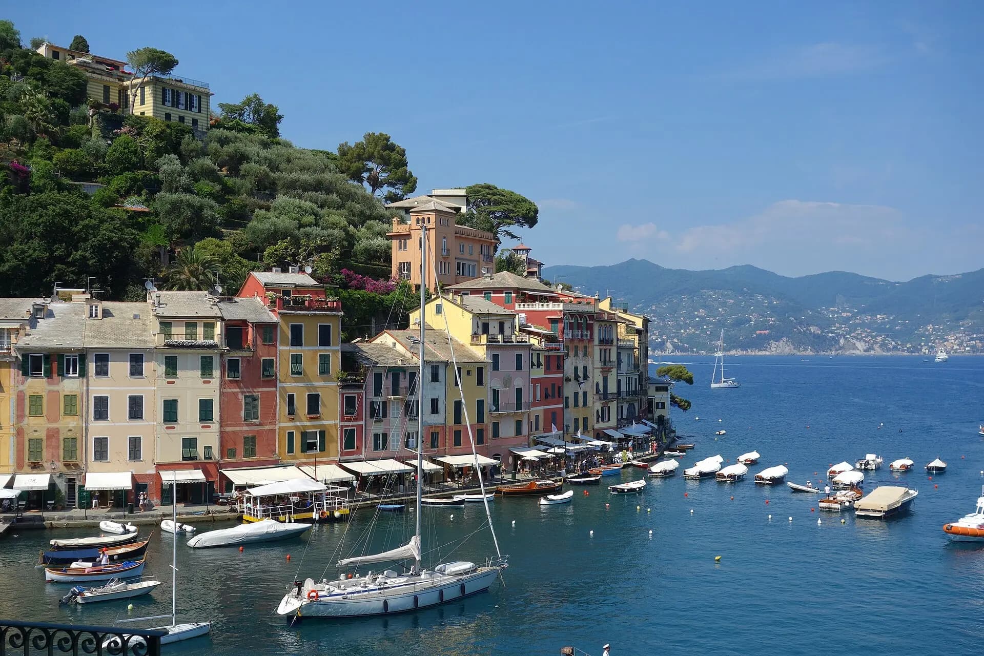 Der Hafen von Portofino mit bunten Häusern und Segelbooten, im Hintergrund der Golf von Tigullio