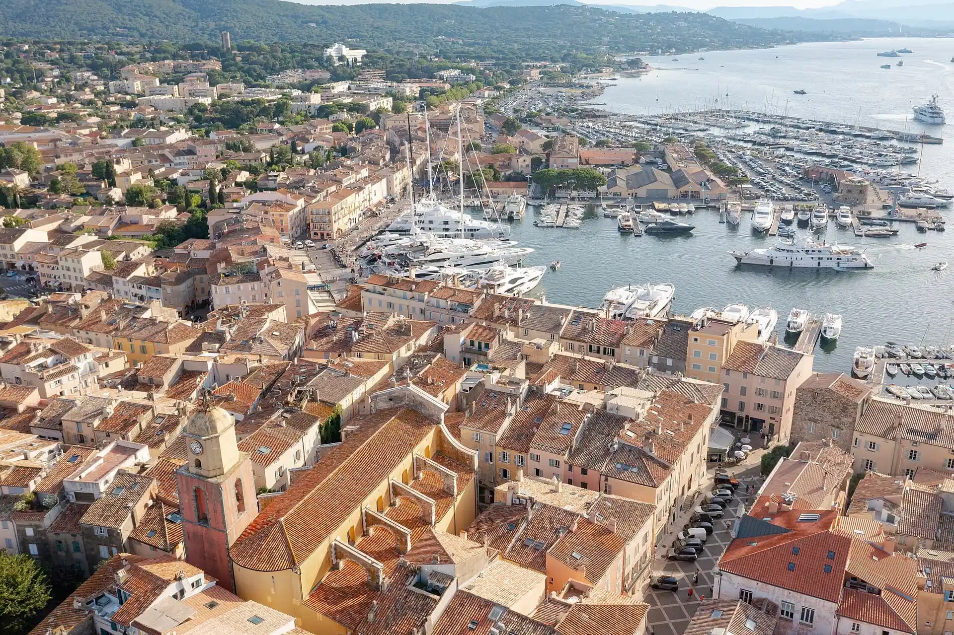 Luftbild von Saint-Tropez mit dem Glockenturm von Notre-Dame-de-l'Assomption, ockerfarbenen Dächern und dem Jachthafen